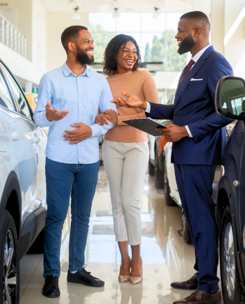 Couple in dealership talking to sales person and buying new car